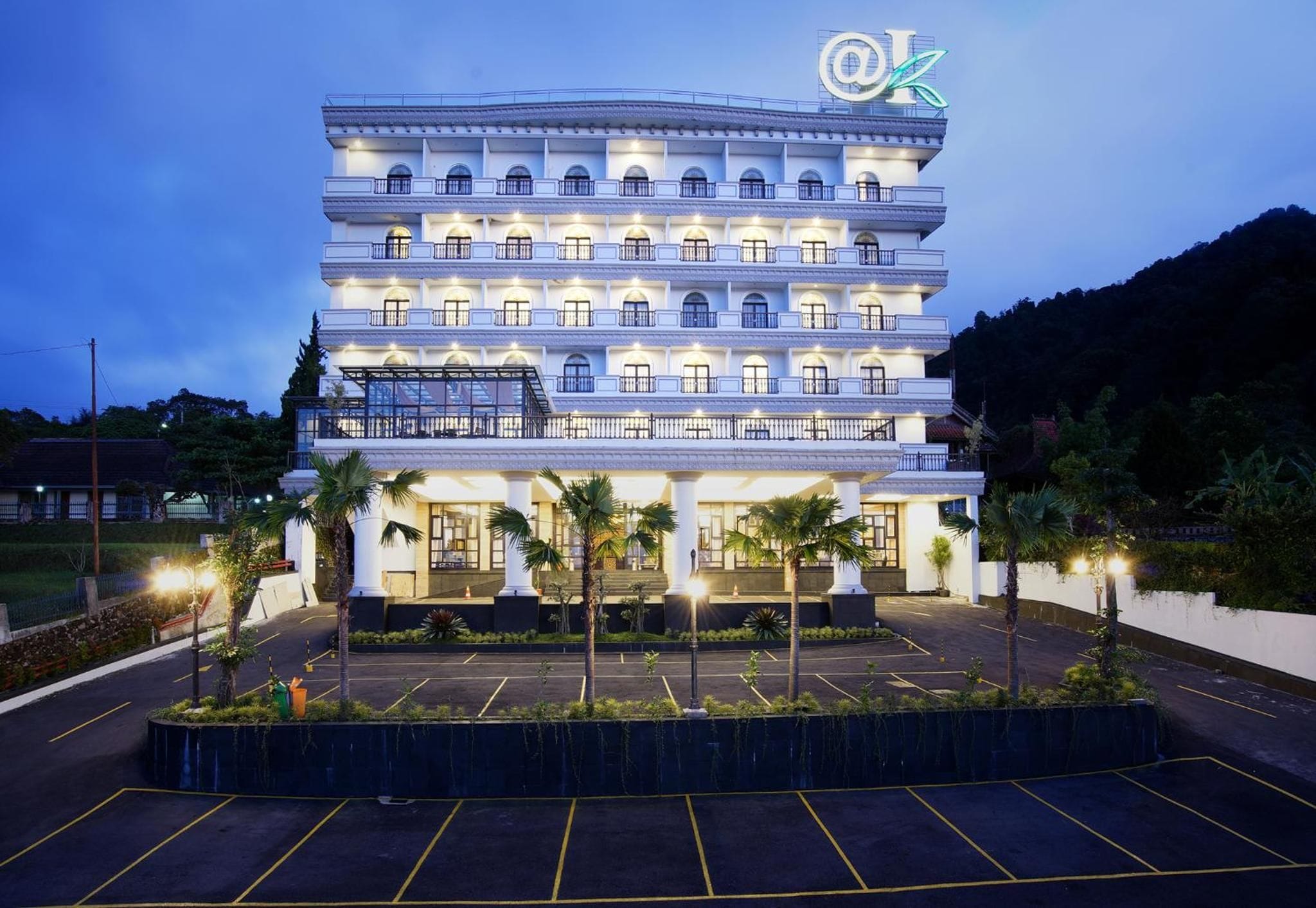 A multi-story hotel with a large parking lot and palm trees in front.