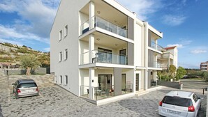 Un immeuble résidentiel moderne à deux étages, doté d’un toit plat, de grandes fenêtres et de balcons.