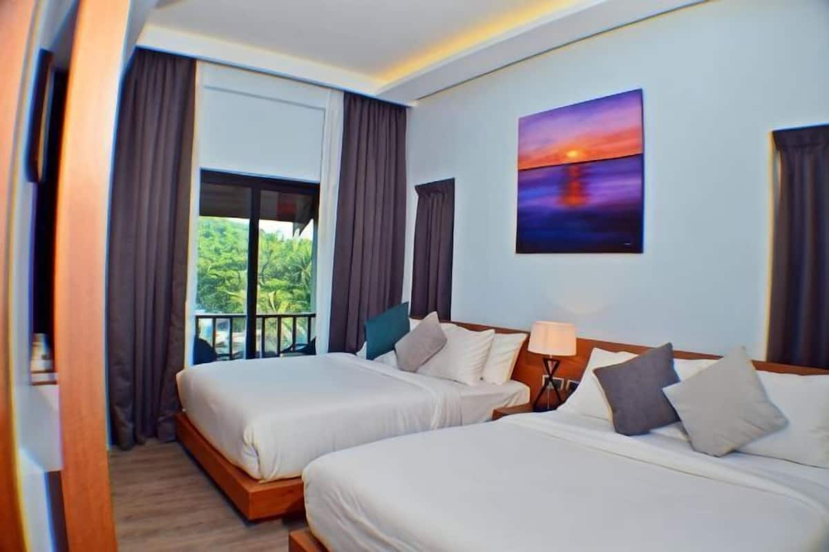 A hotel room with two beds, a balcony, a painting, and a view of greenery.