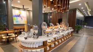 A buffet setup with various food containers and a coffee station, surrounded by wooden tables and chairs. - Mimpi Perhentian (Pulau Perhentian Kecil)