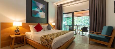 A hotel room with a large bed, two bedside tables with lamps, a chair, a balcony with a view of greenery, and a painting on the wall.