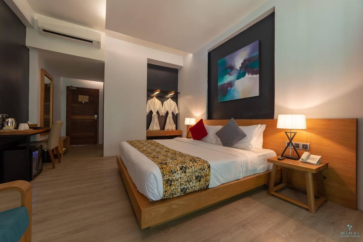 A hotel room with a large bed, bedside tables, a desk, and a wardrobe.