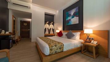 A hotel room with a large bed, bedside tables, a desk, and a wardrobe.
