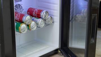 A compact refrigerator with a freezer compartment, containing several cans of beverages.