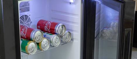 A compact refrigerator with a freezer compartment, containing several cans of beverages.