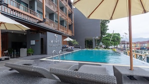 A poolside area with lounge chairs, a pool, and a building with a sign reading "MIMPI LONG BEACH PERHENTIAN". - Mimpi Perhentian (Pulau Perhentian Kecil)