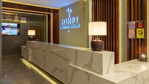 A hotel reception area with a marble counter, a television, and a neon sign reading "MIMPI LONG BEACH PERHENTIAN". - Mimpi Perhentian (Pulau Perhentian Kecil)