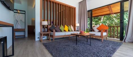 A modern living room with a sofa set, a coffee table, and a large window with a view of greenery.