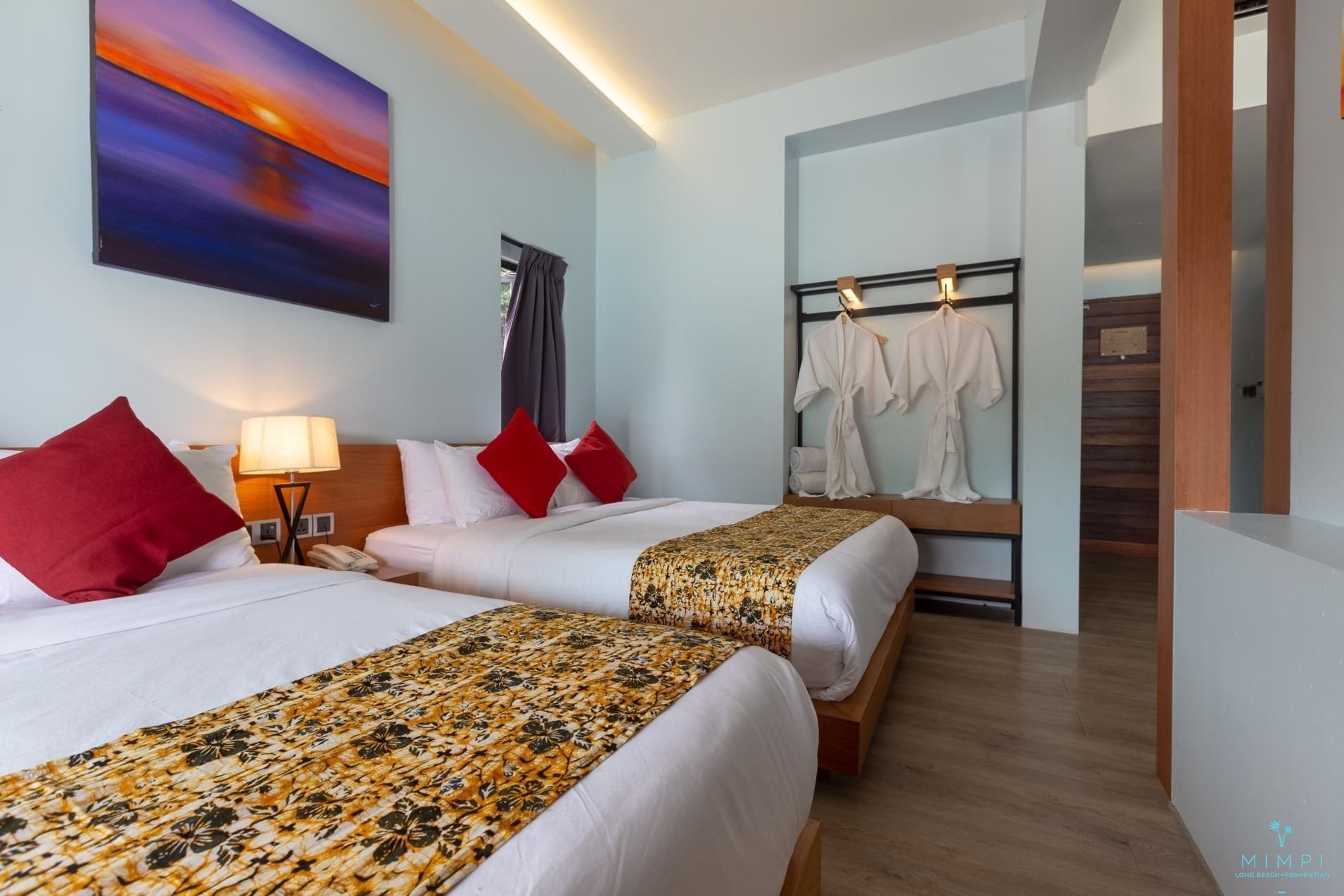A hotel room with two beds, a painting on the wall, a robe rack, and a wooden floor.