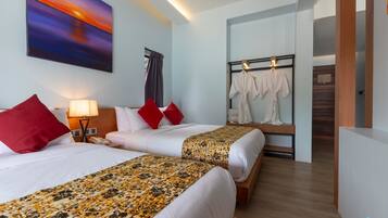 A hotel room with two beds, a painting on the wall, a robe rack, and a wooden floor.