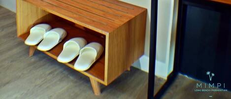 A room with a wooden bench with shoe slots, a large mirror, and a black cabinet.