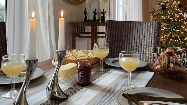 Une table à manger décorée avec des bougies, des verres et un sapin de Noël.