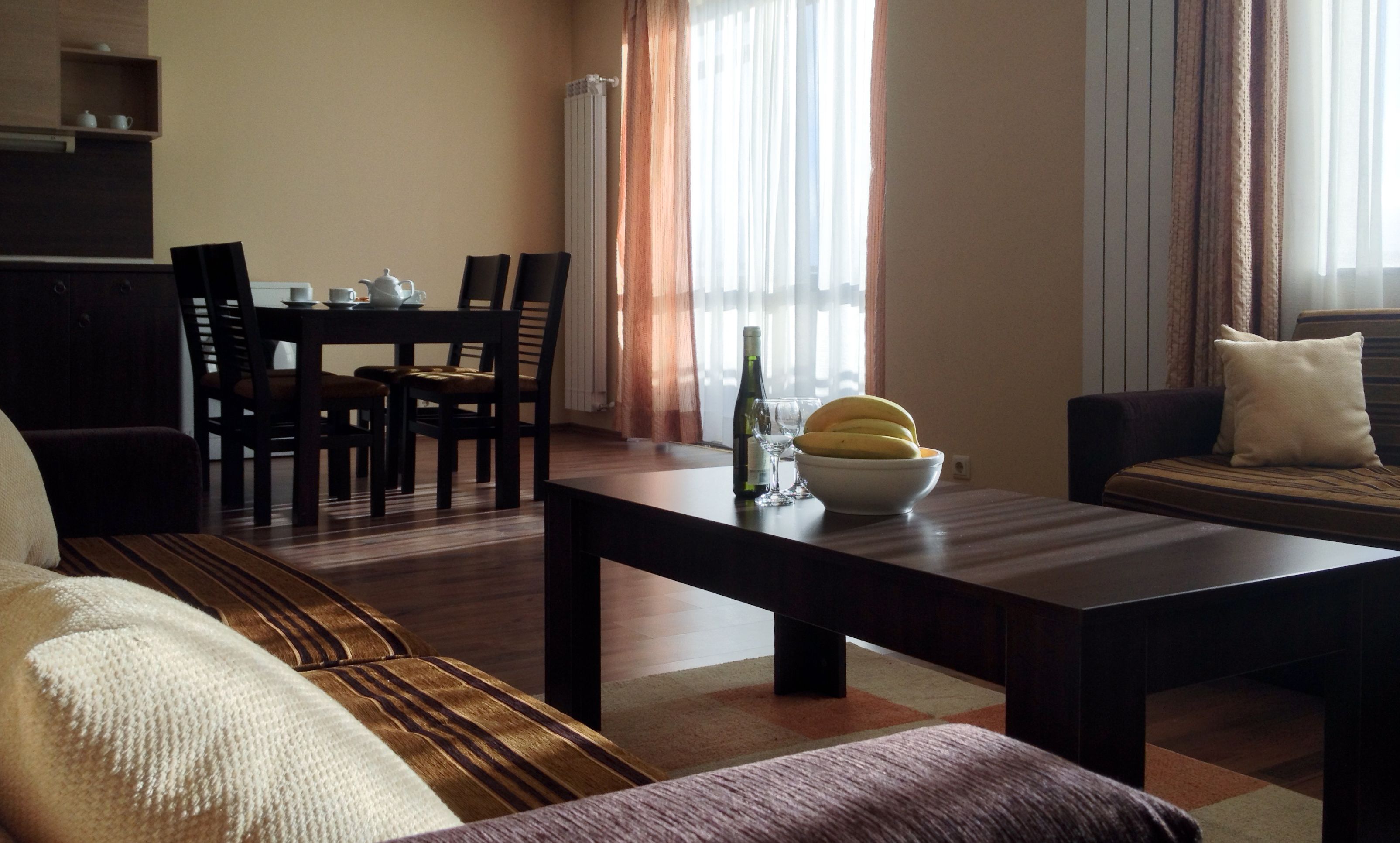 Un salon comprenant un canapé, une table basse, une table à manger avec des chaises et une fenêtre avec des rideaux.