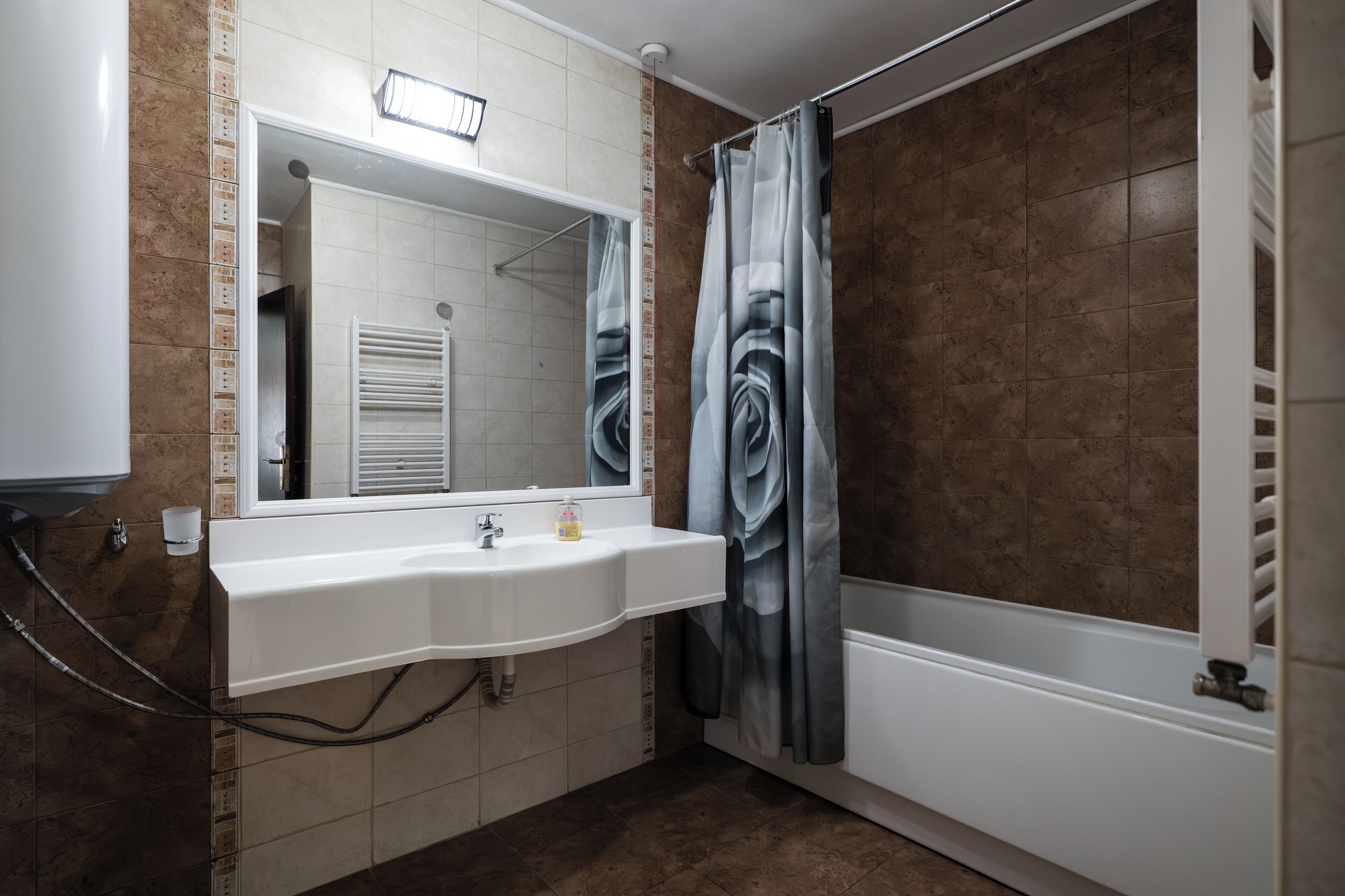Un baño con lavamanos blanco, espejo y cortina de ducha.