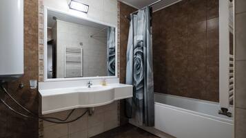 Un baño con lavamanos blanco, espejo y cortina de ducha.