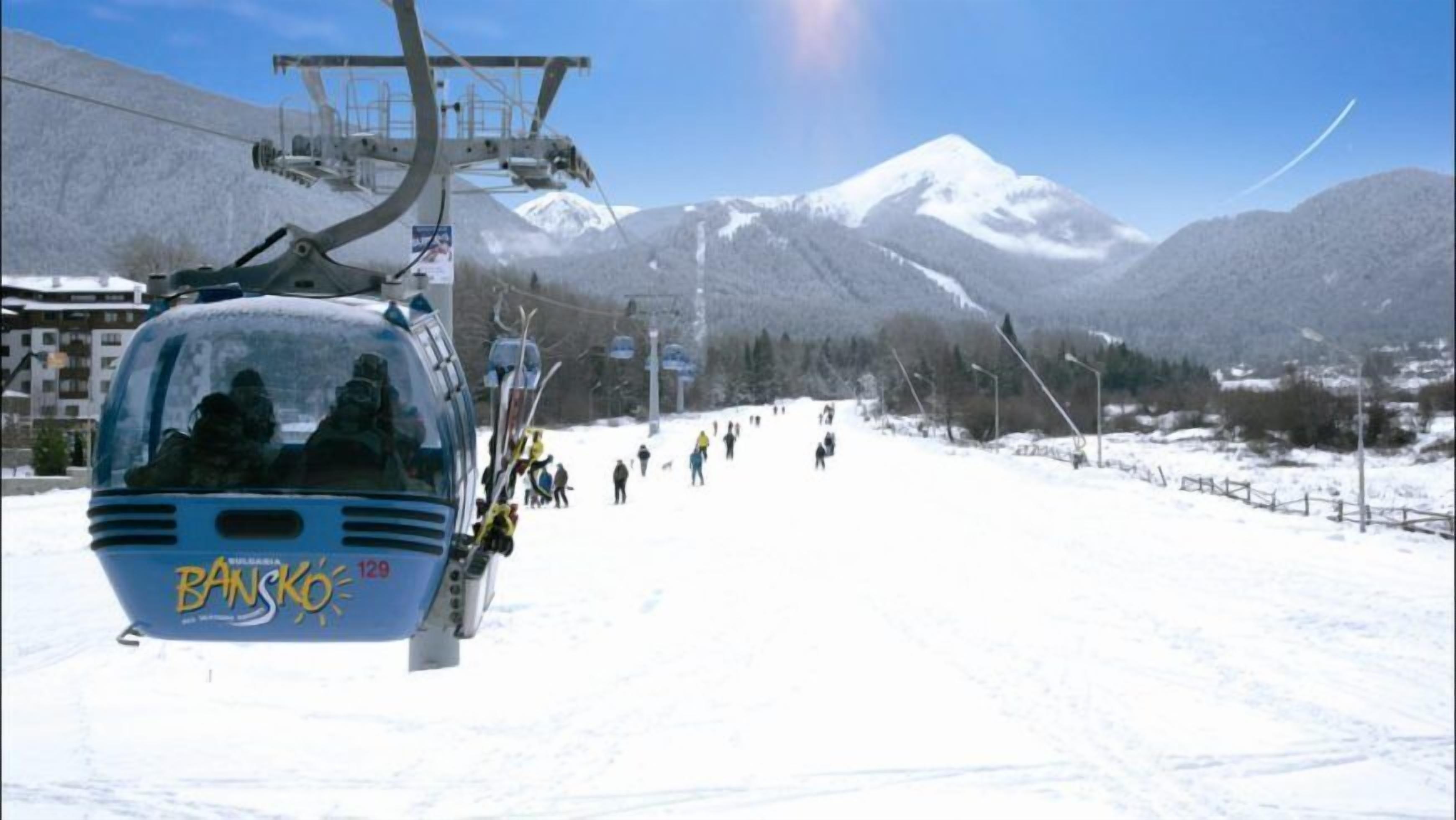 A ski lift with passengers, a snowy mountain slope, and a clear sky.