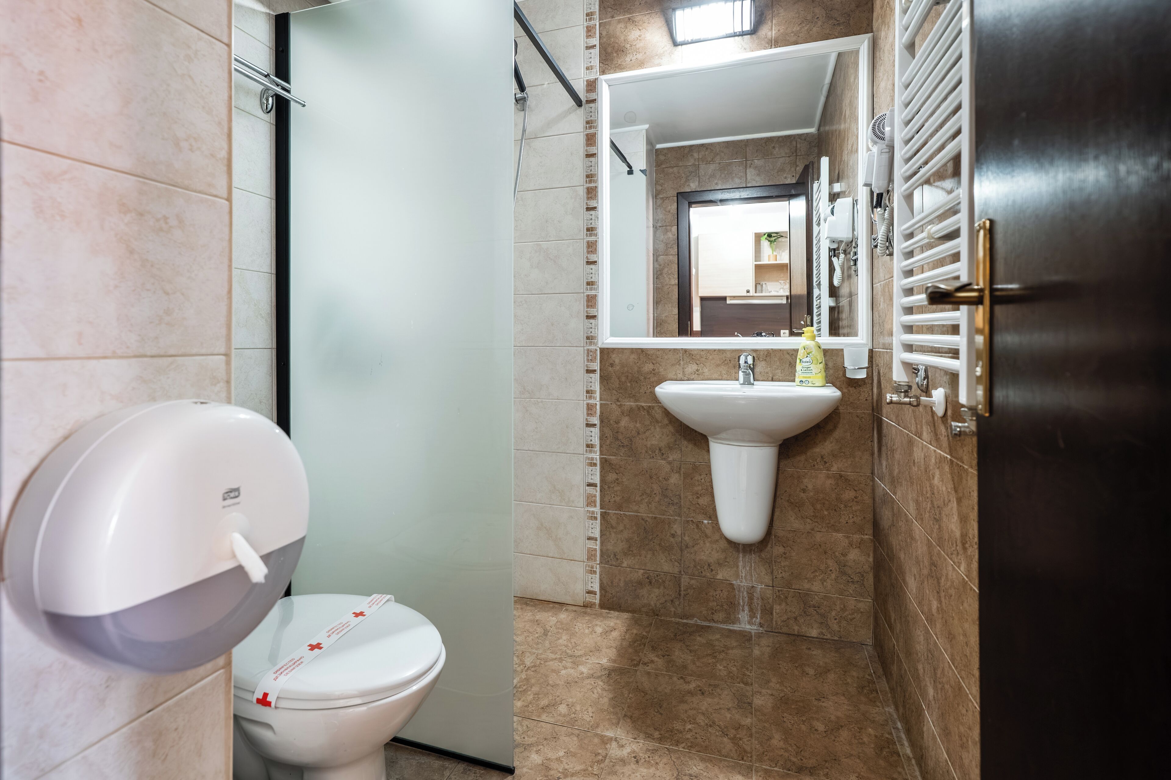 A bathroom with a toilet, sink, and hand dryer.
