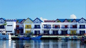 A row of colorful buildings with balconies, a marina with boats, and a clear blue sky. - Sara's House (Hualien City)