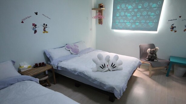 A bedroom with a bed, a small table with cups, a chair, and a window with a pattern. - Sara's House (Hualien City)