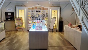 Zona de recepción de un hotel con mostrador, exhibición de artículos de aseo y cartel con el nombre del hotel.