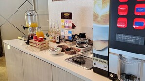 Minibar de una habitación de hotel con una máquina de café, dispensador de bebidas y diversas opciones para beber.