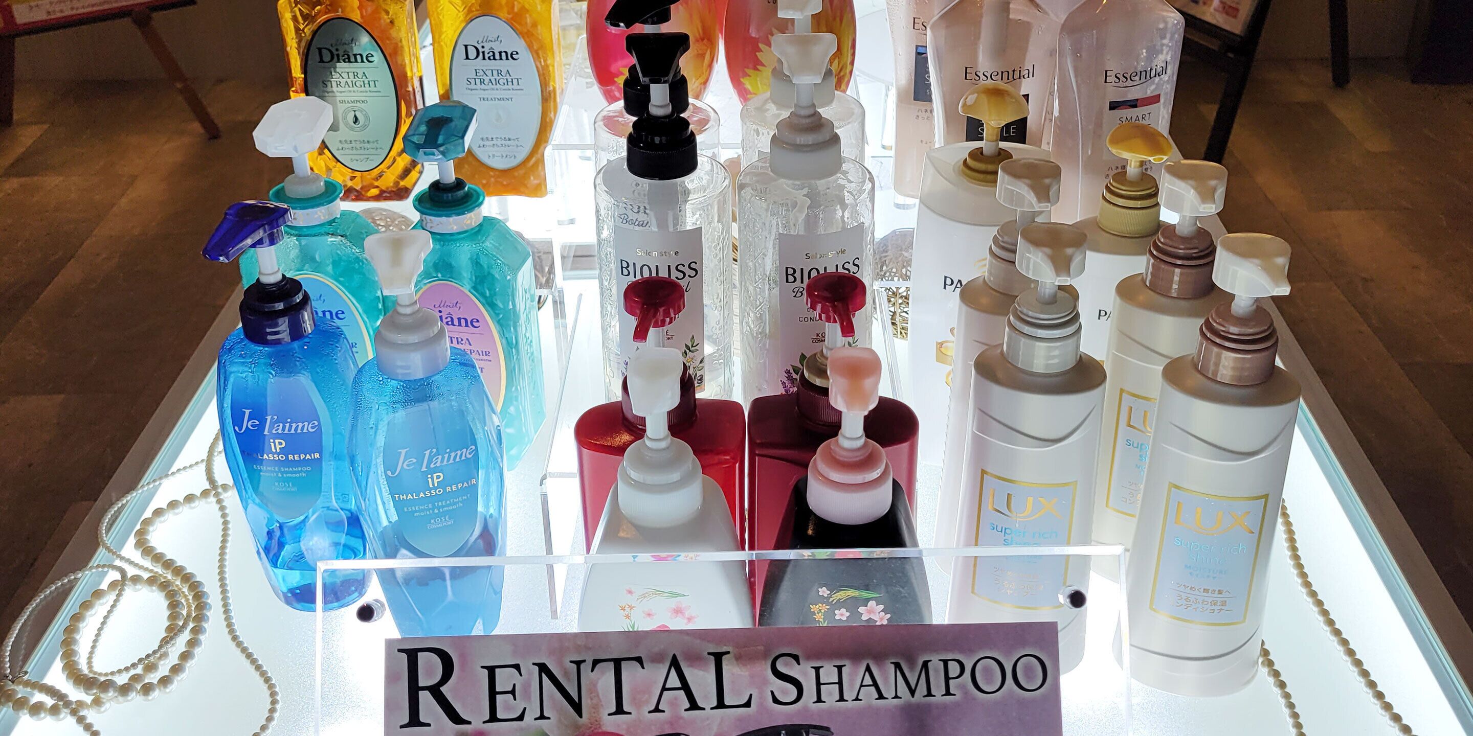 Un présentoir avec différents types de shampooings, accompagné d'une pancarte indiquant « SHAMPOO À LOUER ».