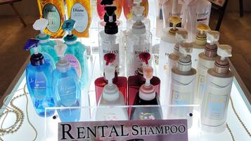 Un présentoir avec différents types de shampooings, accompagné d'une pancarte indiquant « SHAMPOO À LOUER ».