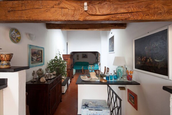 A cozy interior with a wooden ceiling, a dining area with a table set, a sofa, and a painting on the wall.