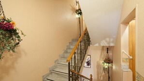 A marble staircase with a wooden handrail and metal balusters, leading to a landing with a wall-mounted light fixture and a small window. - Pensión San José (Bullas)