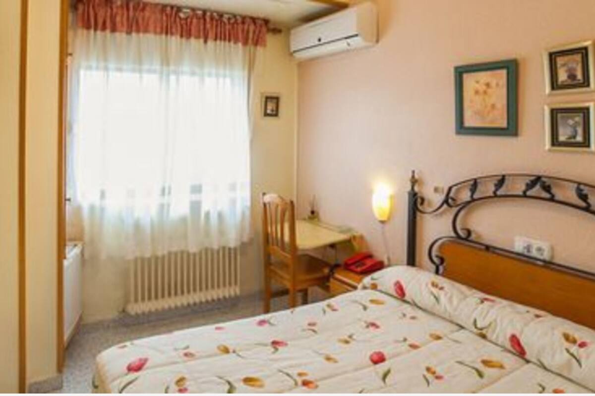 A bedroom with a bed, a desk, and a chair.