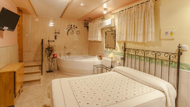 A bedroom with a large bed, a bathtub, and a wooden desk. - Pensión San José (Bullas)