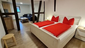 A bedroom with a white bed, red striped bedding, a wooden floor, and a small wooden stool. - Mosel - Bernkastel-Kues - Holiday House "Half-timbered house with charm"  (Bernkastel-Kues)