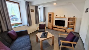 A modern living room with a sofa, armchairs, a coffee table, a TV, and a wooden cabinet. - Mosel - Bernkastel-Kues - Holiday House "Half-timbered house with charm"  (Bernkastel-Kues)