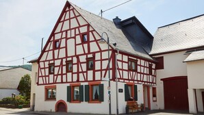 A traditional half-timbered house with a steep gabled roof, a red door, and a small porch with a bench. - Mosel - Bernkastel-Kues - Holiday House "Half-timbered house with charm"  (Bernkastel-Kues)