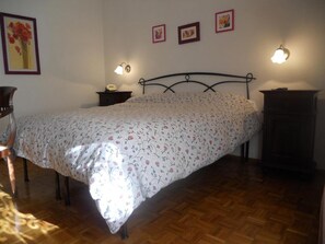 A bedroom with a bed, wooden floor, bedside tables, and wall-mounted lamps. - Albergo Generale Cantore (Abbadia San Salvatore)