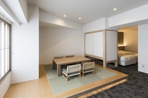 A modern room with a wooden dining table, two chairs, a sofa, and a large wardrobe. - New Tomakomai Prince Hotel Nagomi (Tomakomai)