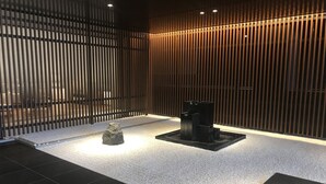 A modern interior with a wooden slat wall, a black tiled floor, and a central black structure. - New Tomakomai Prince Hotel Nagomi (Tomakomai)