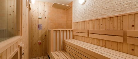 A wooden sauna with benches and a clock on the wall.