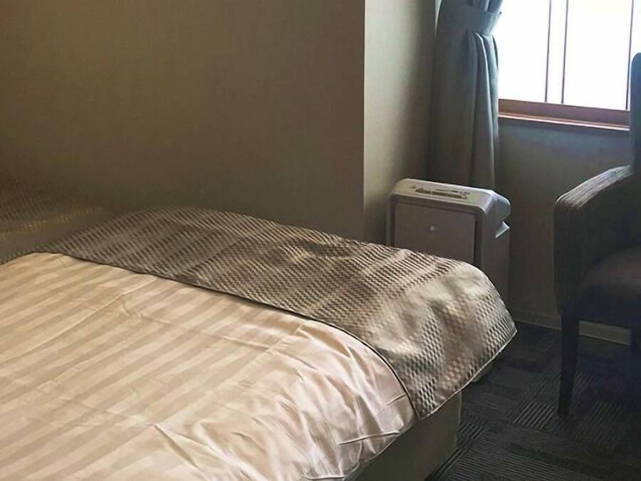 Una habitación de hotel con dos camas, un radiador y una silla.