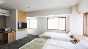 A hotel room with two beds, a TV, a desk with a microwave, and large windows.