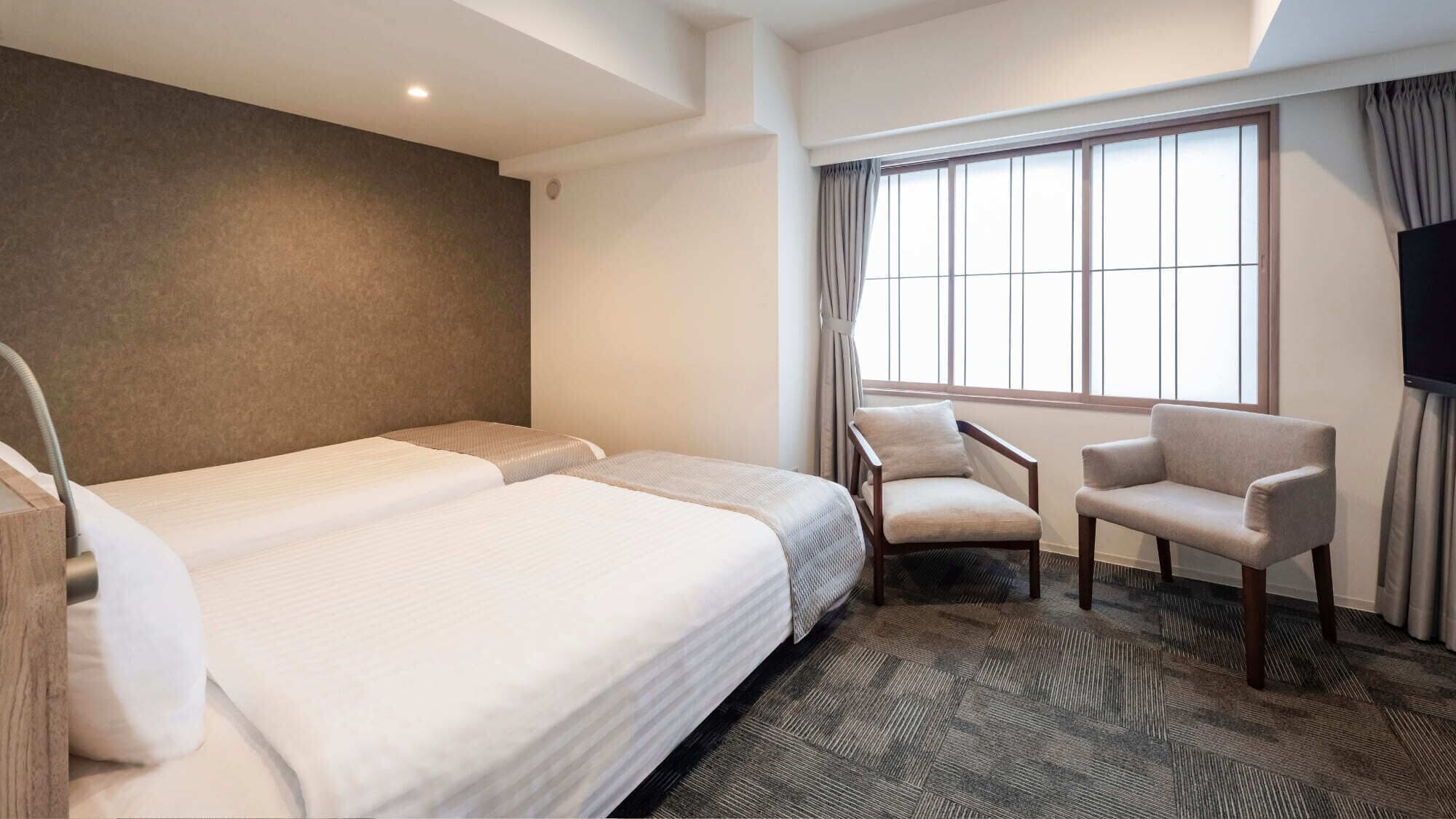 Habitación de hotel con dos camas, una silla, un televisor y un ventanal grande.