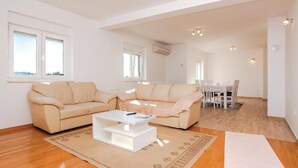 Un salon moderne avec un canapé beige, une table basse blanche et un coin repas comprenant une table et des chaises.
