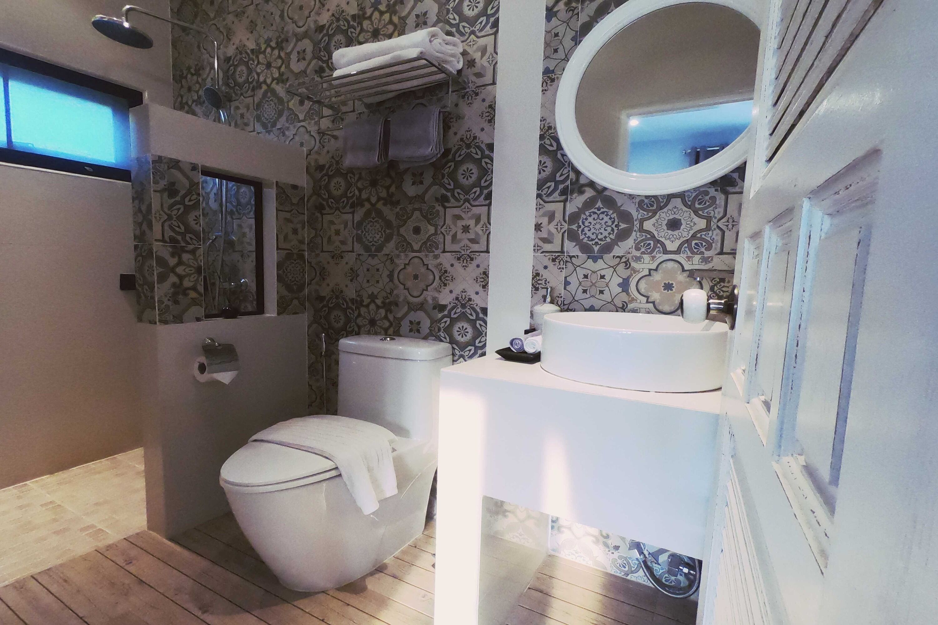 A bathroom with a toilet, a sink, a mirror, and a shower.