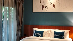 Habitación de hotel con una cama grande, cabecera con almohada que dice 'My Destiny', aire acondicionado de pared y una ventana con cortinas de gasa.