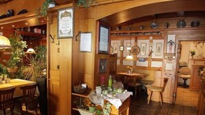 Un acogedor interior de restaurante con decoración de madera, un mostrador central con un arreglo floral y varias fotografías enmarcadas en las paredes.