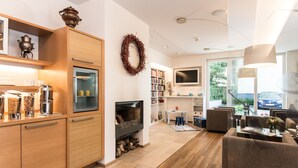 A modern living room with a fireplace, wooden cabinets, a television, and a bookshelf. - Baurs Park (Hamburg)