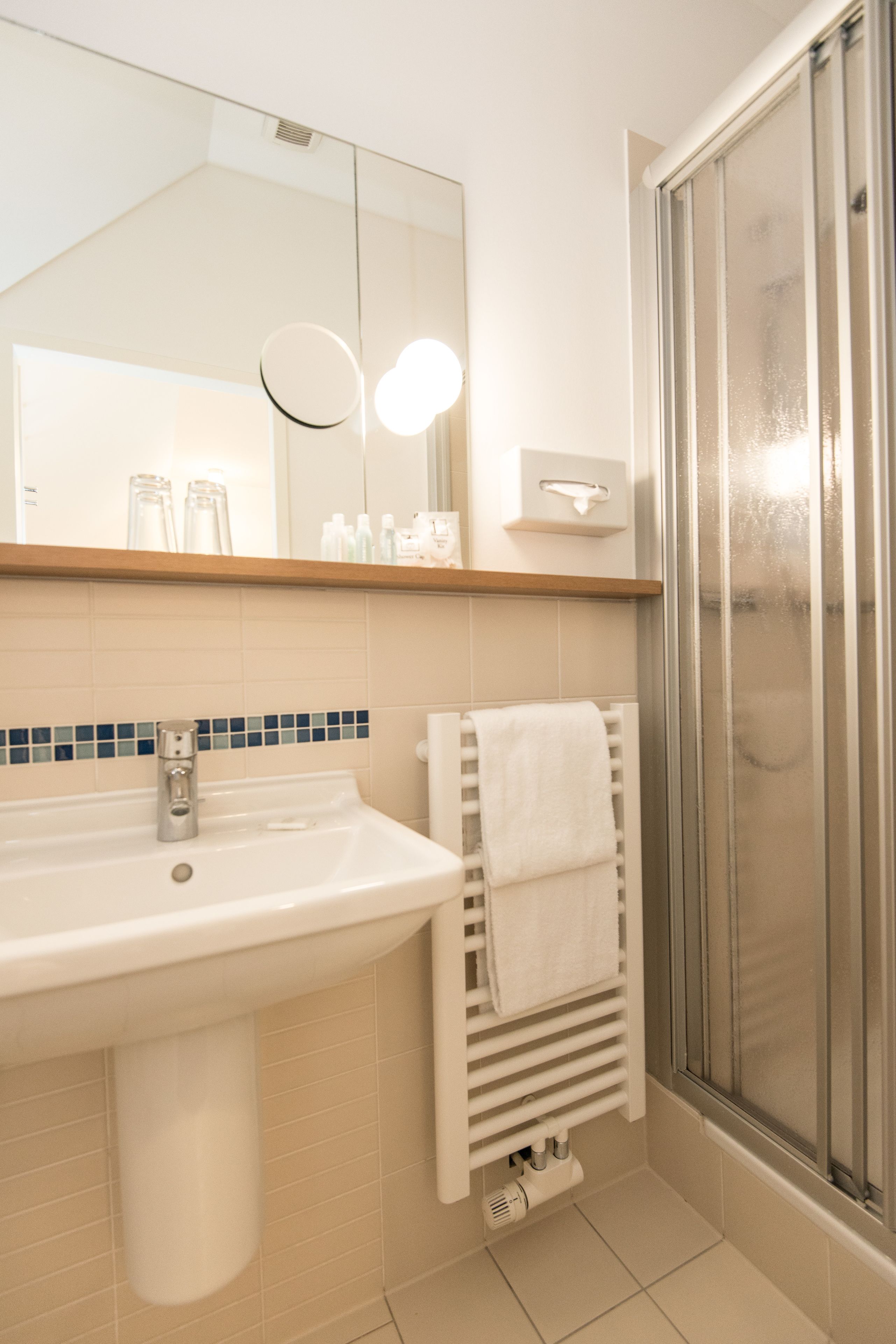 A bathroom with a sink, mirror, and shower.