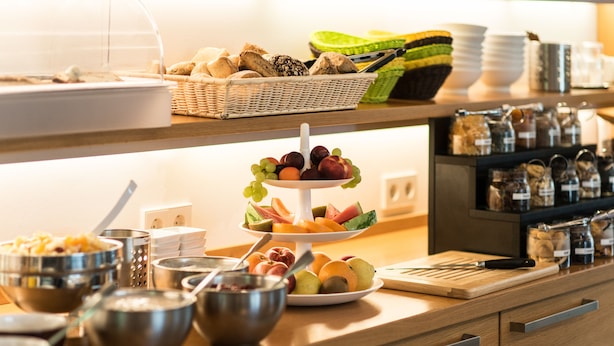 A buffet setup with various food items, including fruits, breads, and condiments. - Baurs Park (Hamburg)