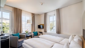 A hotel room with a large bed, a desk with a lamp, a chair, and a TV on the wall. - Baurs Park (Hamburg)