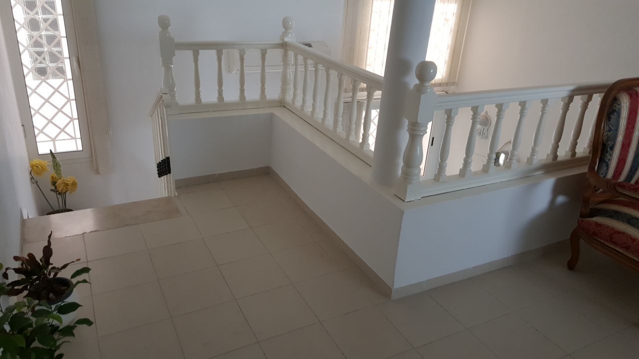 Eine Treppe mit weißen Geländern und einem Blumentopf am Fuß.